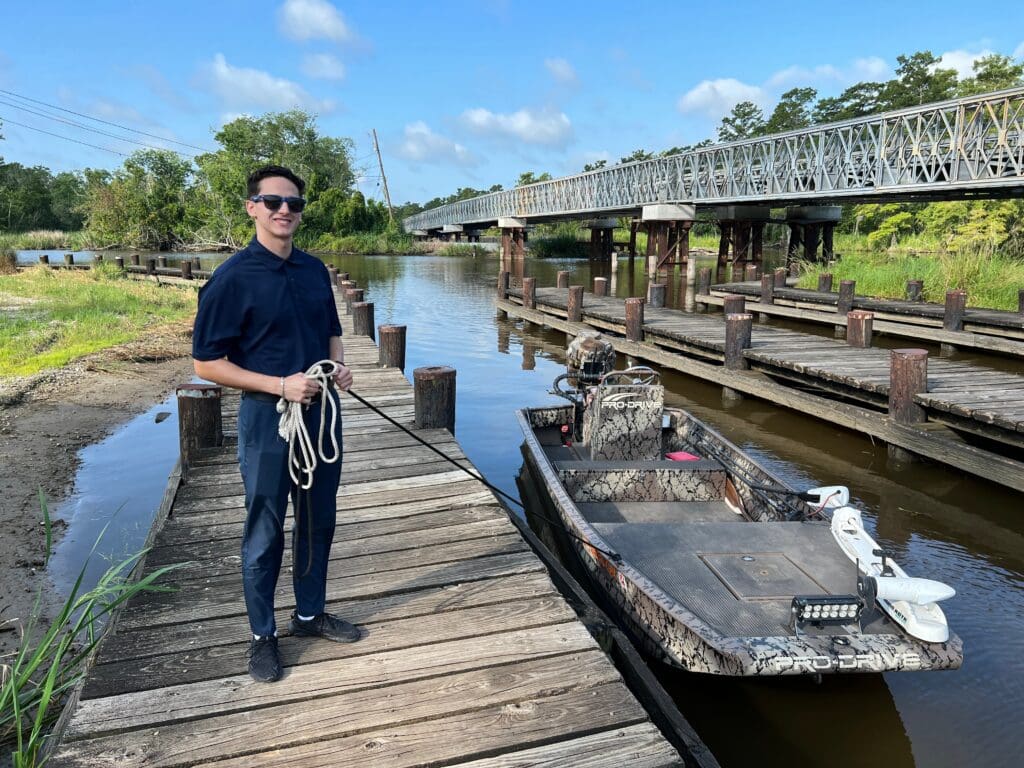 Mosaic Property Valuations intern stands on a dock holding a line connected to a small boat in the water