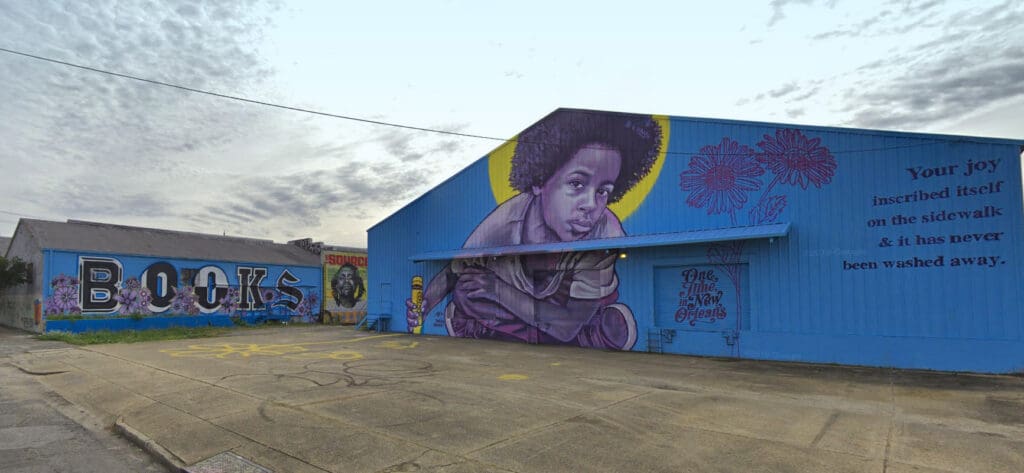 2900 Dauphine buildings with murals painted by New Orleans artist BMIKE. Murals include "BOOKS," a child drawing, "One Time in New Orleans," two flowers, "Your joy inscribed itself on the sidewalk & it has never been washed away."